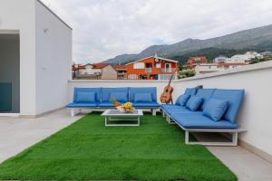 Un balcón con sofás azules y una alfombra verde. en Villa Srdella, en Podstrana