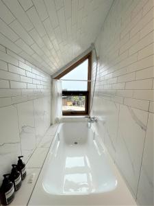 a white bath tub in a bathroom with a window at Walden Studios in Seogwipo