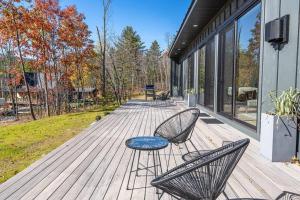 a wooden deck with two chairs and a table at Lux Modern Barnhouse Cabin at Hunter Mountain in Hunter