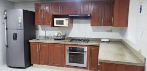 a kitchen with wooden cabinets and a stainless steel refrigerator at Hotel Nueva Tequendama in Cali