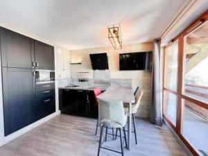 a kitchen with black cabinets and a table and chairs at Studio Valloire, 1 pièce, 4 personnes - FR-1-263-527 in Valloire