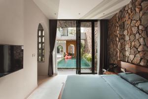 a bedroom with a bed and a stone wall at Gom House in Da Nang