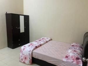 um pequeno quarto com uma cama e uma cómoda em Ajila Inn em Sepang
