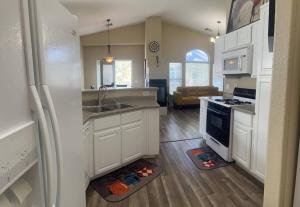a kitchen with white cabinets and a sink and a refrigerator at Gorgeous home away from home in Las Vegas
