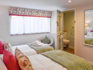 a bedroom with two beds and a window and a bathroom at Reedham Retreat in Reedham