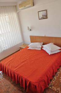 a red bed with white pillows in a bedroom at Hotel Lido in Mamaia