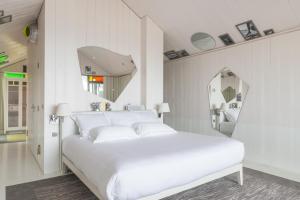 a white bedroom with a white bed and a mirror at Hotel La Co(o)rniche in Pyla-sur-Mer