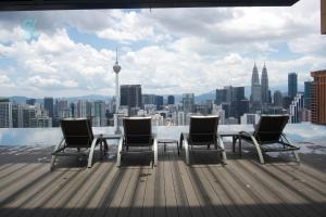 a table and chairs on a roof with a view of a city at Harmony Luxury Suites At Lucentia Bukit Bintang City Center in Kuala Lumpur