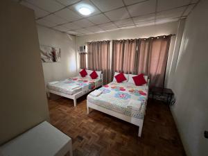 ダバオシティにあるGolden Belle Apartelle and Suitesの赤い枕が備わる小さな部屋のベッド2台