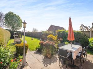 un jardín con mesa y sombrilla en Langford Cottage, en Ringstead