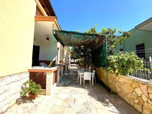トッレ・カンネにあるVilla Flower Holiday Torre Canne - 5min dalla spiaggiaの建物の隣にテーブルと椅子付きのパティオ
