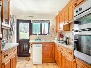 una cocina con armarios de madera y fregadero en Langford Cottage, en Ringstead