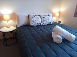 uma cama num quarto com lençóis e almofadas azuis em Forster Palms Motel em Forster