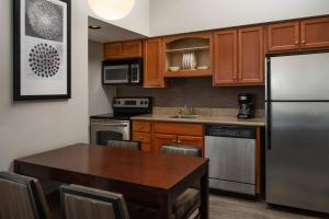 a kitchen with a table and a stainless steel refrigerator at Residence Inn Seattle North/Lynnwood Everett in Lynnwood
