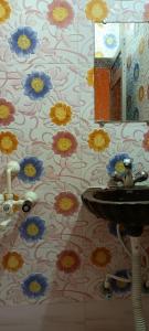 baño con lavabo y flores en la pared en MONIKA MANSION Bodhgaya, en Bodh Gaya