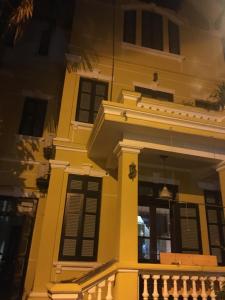 a yellow house with black shutters and a balcony at French-styled house in Hanoi
