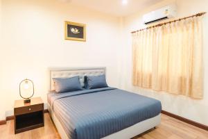 Schlafzimmer mit einem Bett mit blauer Bettwäsche und einem Fenster in der Unterkunft Kai Mook House in Ban Ket Ho
