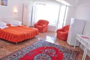 een slaapkamer met een bed en 2 stoelen en een koelkast bij Hotel Lido in Mamaia
