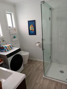 a bathroom with a shower and a toilet at Adorable Beach Unit Stanmore Bay in Whangaparaoa