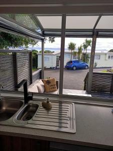 a kitchen with a sink and a view of a parking lot at Adorable Beach Unit Stanmore Bay in Whangaparaoa