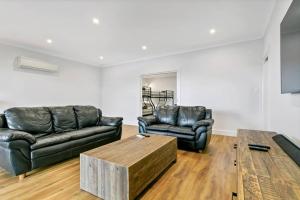 Platinum on Washpool في Wellington East: غرفة معيشة مع كنبتين جلديتين وطاولة قهوة