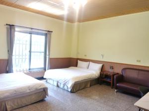 um quarto com duas camas e uma cadeira e uma janela em Alishan Tea Homestay em Leye