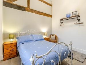 a bedroom with a bed with a blue comforter at The Parlour - Uk41748 in Loppington
