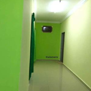 une chambre verte avec un mur vert et une télévision dans l'établissement GREENS HOMESTAY, à Sungai Besar