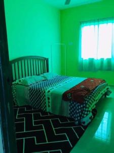 a green bedroom with a bed in a room at GREENS HOMESTAY in Sungai Besar