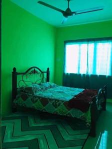 - une chambre verte avec un lit et une fenêtre dans l'établissement GREENS HOMESTAY, à Sungai Besar