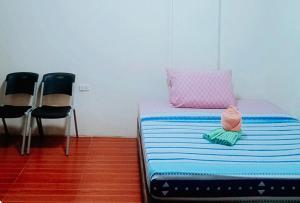 een slaapkamer met een bed met een kussen en 2 stoelen bij RedDoorz @ 4ks Pension House Bogo City Cebu in Banban