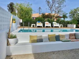 a white couch with pillows sitting next to a pool at Casa Pedra Rosa - VINHAS de NEXE in Faro