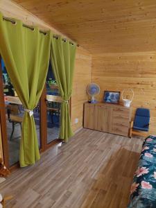 a room with a bed and a window with green curtains at Cabana Oprișor in Ocna Sibiului