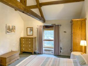 a bedroom with a bed and a dresser and a window at Barn End Cottage in Millers Dale