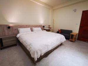 een slaapkamer met een groot wit bed en een stoel bij 小短腿的家-無人化民宿 in Taitung