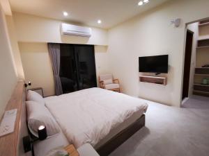 a bedroom with a white bed and a television at 小短腿的家-無人化民宿 in Taitung City