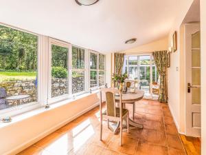 a dining room with a table and large windows at Kennel Cottage in Alwinton