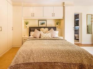 a bedroom with a large bed and white cabinets at Kennel Cottage in Alwinton