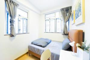 a small bedroom with a bed and two windows at Shared Apartment Lockhart Road 384 in Hong Kong