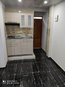 cocina con armarios blancos y suelo negro en Apartamentos Olaya!, en Bahía Solano