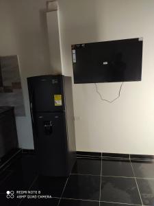 einen schwarzen Kühlschrank mit einem Flachbild-TV an der Wand in der Unterkunft Apartamentos Olaya! in Bahía Solano