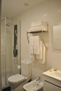 a bathroom with a toilet and a shower and towels at Apartamentos Portodouro - Santa Catarina in Porto