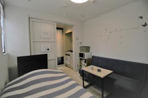 a bedroom with a bed and a table and a white wall at Fukuoka Single Room in Fukuoka