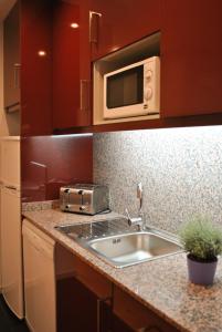 a kitchen with a sink and a microwave at Apartamentos Portodouro - Santa Catarina in Porto