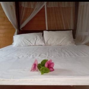 a white bed with a pink flower on it at Gray house up in Weligama