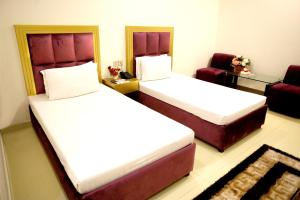 a hotel room with two beds and a couch at Royalton Inn Hotel - Gulberg in Lahore +9 photos