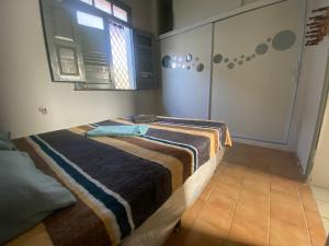 ein Schlafzimmer mit einem Bett mit einer gestreiften Decke in der Unterkunft Quarto com ótimo custo benefício in Parnaíba
