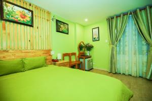 um quarto verde com uma cama grande e uma secretária em Dalat Flowery hotel & coffee em Da Lat