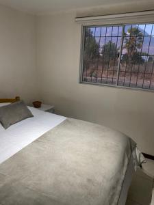 1 cama blanca en un dormitorio con ventana en Casa de Campo, en Santa Cruz