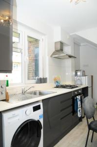 a kitchen with a washing machine and a sink at Greater London, 1 Bed London Flat, Parking, nr Metro Stations, 15mins to London in London
